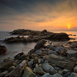 A rocky shoreline with a sunset in the background. - Torre Quimeta 2C in Roses (Roses)