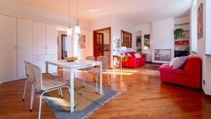 A spacious living area with a dining table, chairs, a red sofa, and a kitchen in the background. - Gerbett Apartment with Terrace by Wonderful Italy (Como)