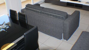 A modern living room with a grey sofa, a dining table with chairs, and a flat-screen TV mounted on the wall. - Drugstore B E in Roses (Roses)