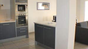 A modern kitchen with built-in appliances and a dining area with a dark sofa. - Drugstore B E in Roses (Roses)