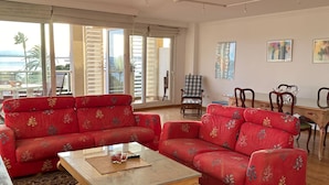 A spacious living room with a red sofa set, a wooden coffee table, and a view of the ocean through large sliding glass doors. - Virgen del Rocio in Roses (Roses)
