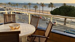 A balcony with a table and chairs overlooking a beach and road. - Virgen del Rocio in Roses (Roses)