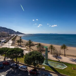 A coastal cityscape with a beach, palm trees, and a clear sky. - Virgen del Rocio in Roses (Roses)