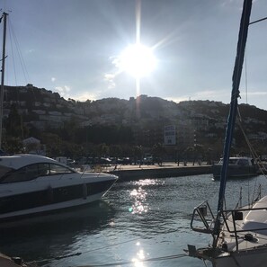 Ein Hafen mit vertäuten Booten, klarem Himmel und Gebäuden im Hintergrund.