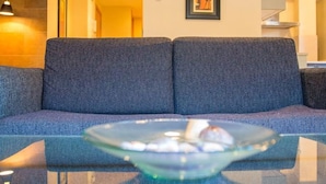Ett modernt vardagsrum med en grå soffa, ett soffbord i glas och en luftkonditioneringsanläggning på väggen.