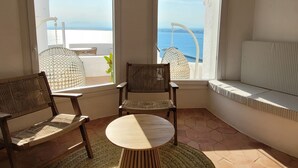 A corner room with two wicker chairs, a small round table, and a bench by the windows overlooking the sea. - Castell Mar 1001 in Roses (Roses)