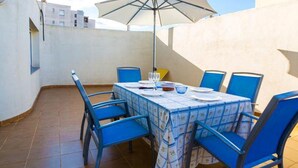 A rooftop terrace with a table set for four, blue chairs, and a large umbrella. - Drugstore B A in Roses (Roses)