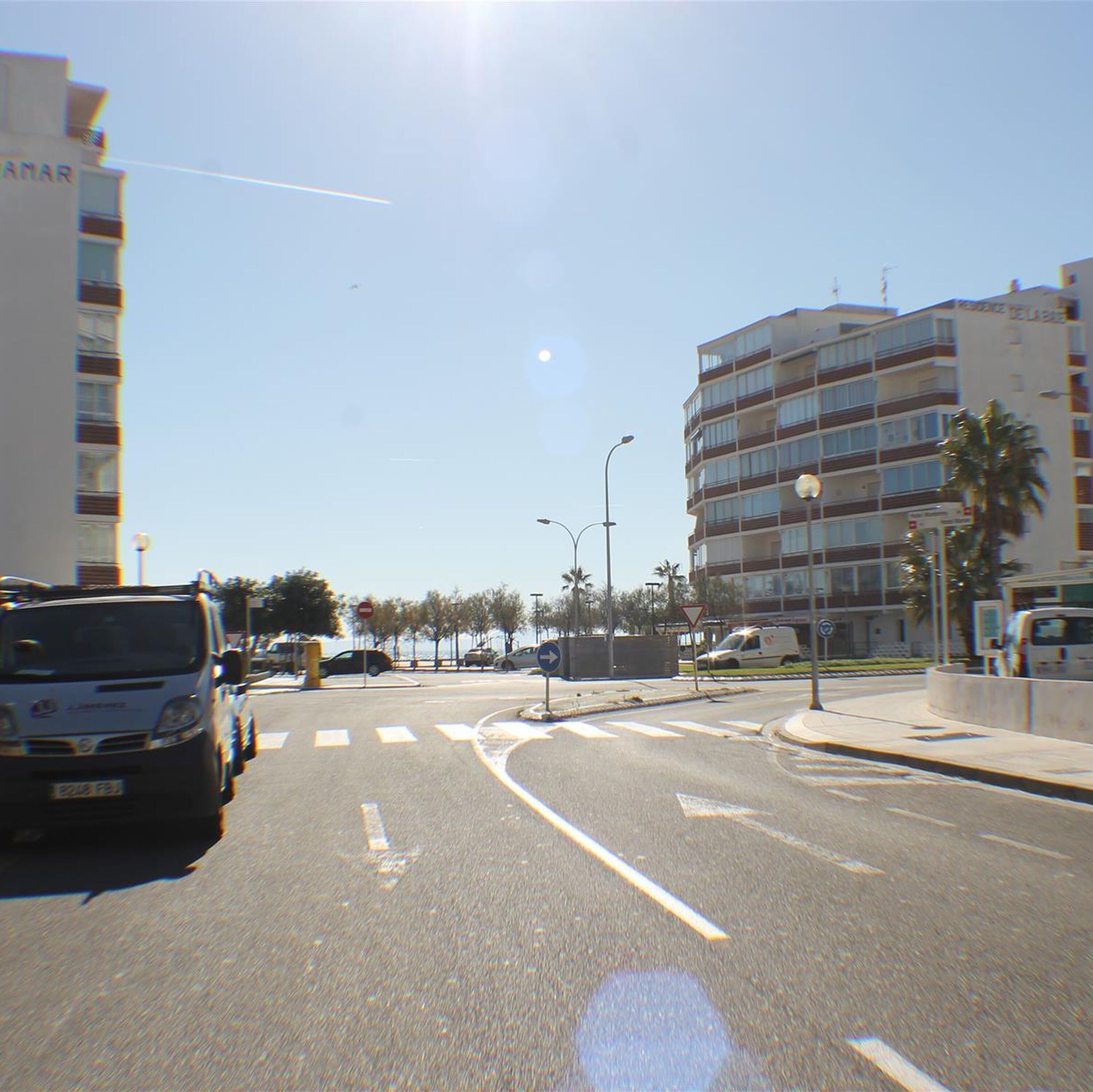 A street view with a multi-story building, a clear sky, and a parked van.