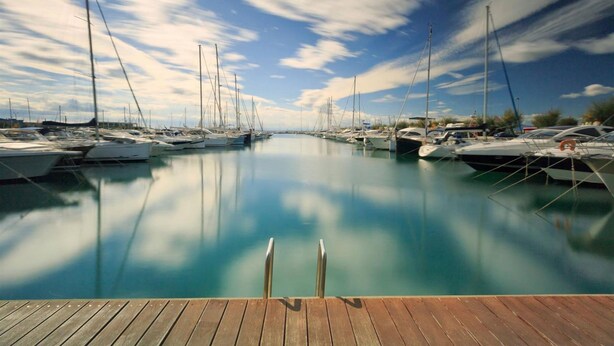 A marina with boats docked, calm water, and a wooden dock in the foreground. - Holiday Home- Puerto (Roses)