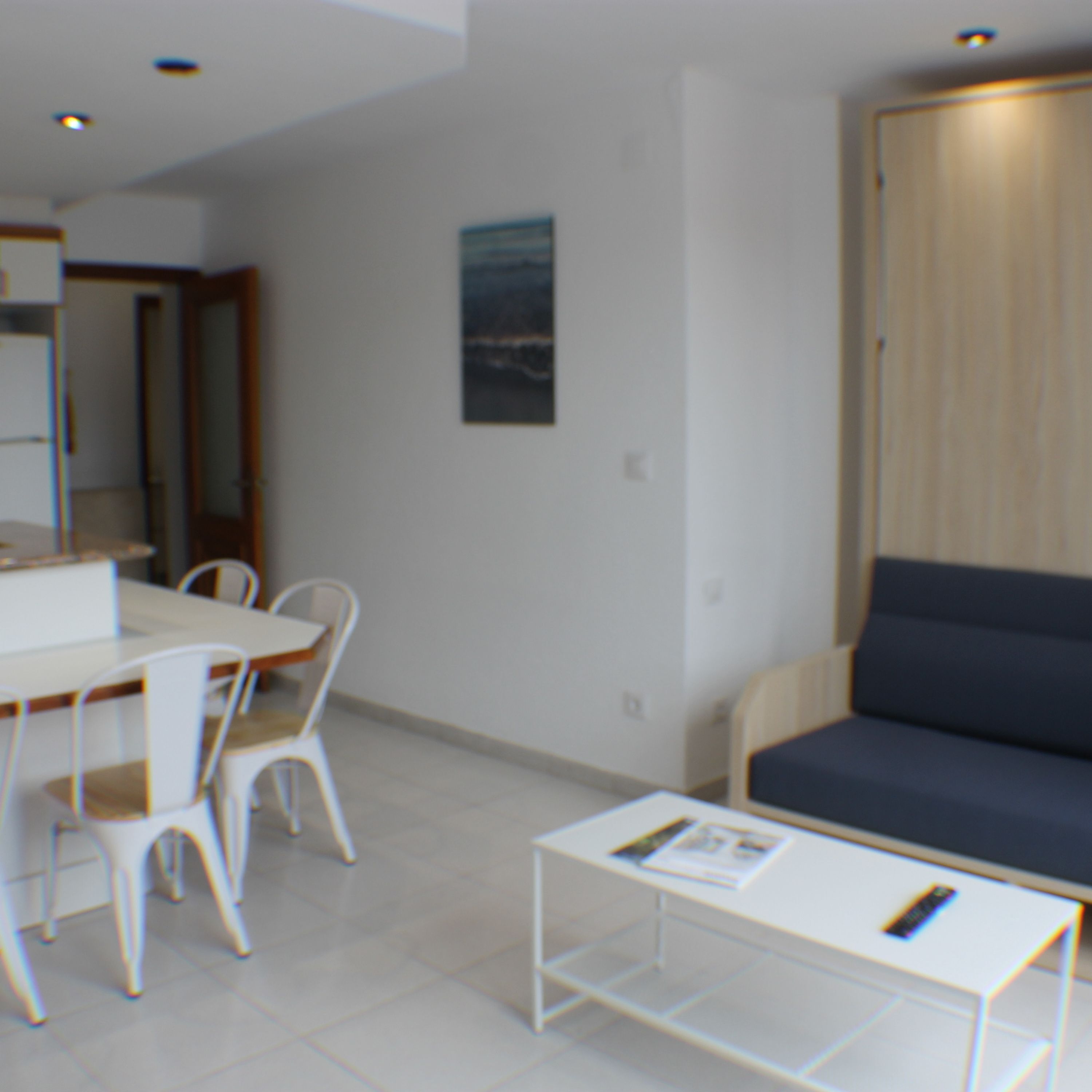 Een moderne woonkamer met een witte bank, een eettafel met stoelen en een kleine witte salontafel.