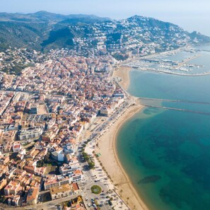 Vista aérea de una ciudad costera con una zona urbana densamente poblada, una extensa playa de arena y un mar azul cristalino.