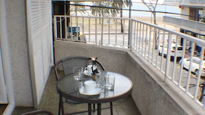 Un piccolo balcone con un tavolo rotondo e due sedie in vimini.