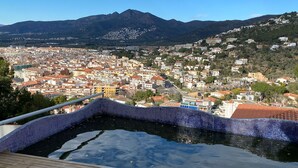 A pool with a tiled edge, overlooking a town with buildings and mountains in the background. - Villa Pamela in Roses (Roses)
