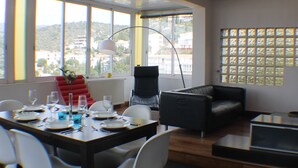 A modern living room with a dining area, large windows, and a view of the city. - Villa Pamela in Roses (Roses)