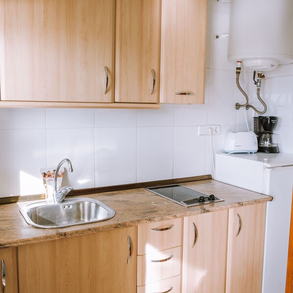 A kitchen with wooden cabinets, a stainless steel sink, a built-in electric stove, and a coffee maker. - Marina 9 in Roses With 1 Bedrooms and 1 Bathrooms (Roses)