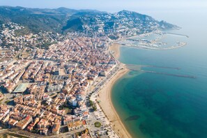 An aerial view of a coastal city with dense urban development, a beach, and a pier extending into the sea. - Drugstore A C in Roses (Roses)