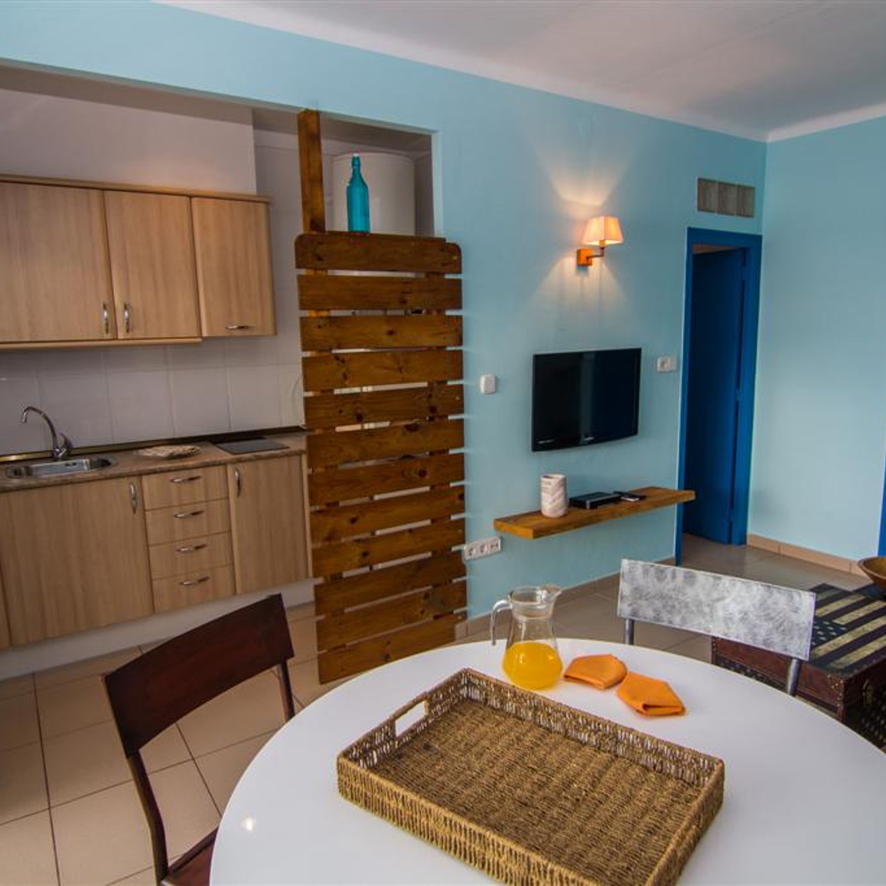 A compact living space with a kitchen, dining area, and a TV mounted on the wall.