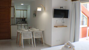 A modern bedroom with a bed, a TV mounted on the wall, and a dining area with a table and chairs. - Pi Sunyer 4 5A in Roses (Roses)