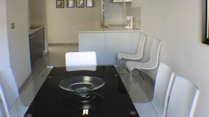 Una cocina moderna con armarios blancos, una campana extractora de acero inoxidable y una cafetera sobre la encimera.