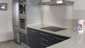 Una cocina moderna con electrodomésticos de acero inoxidable, gabinetes grises y encimera blanca.