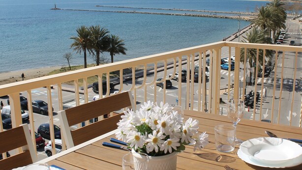 Une table dressée pour le dîner, avec vue sur la mer et des bâtiments en arrière-plan.