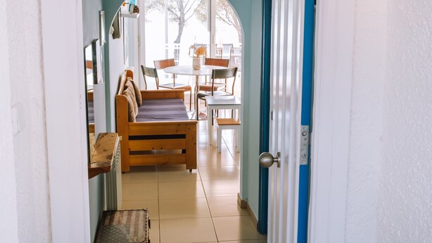 A hallway leading to a dining area with a wooden bench and a table. - Marina 4 in Roses With 1 Bedrooms and 1 Bathrooms (Roses)
