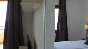 A hotel room with a desk, a bed, and curtains.