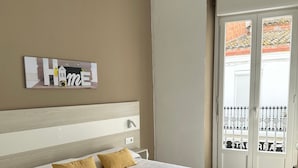 A bedroom with a bed, two pillows, a nightstand, a wall-mounted artwork, and a sliding glass door to a balcony. - Joan Badosa 1 B in Roses (Roses)