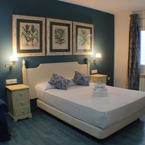 A bedroom with a large bed, two bedside tables, a nightstand, and three framed botanical prints on the wall. - Avenida 5C in Roses With 2 Bedrooms and 2 Bathrooms (Roses)