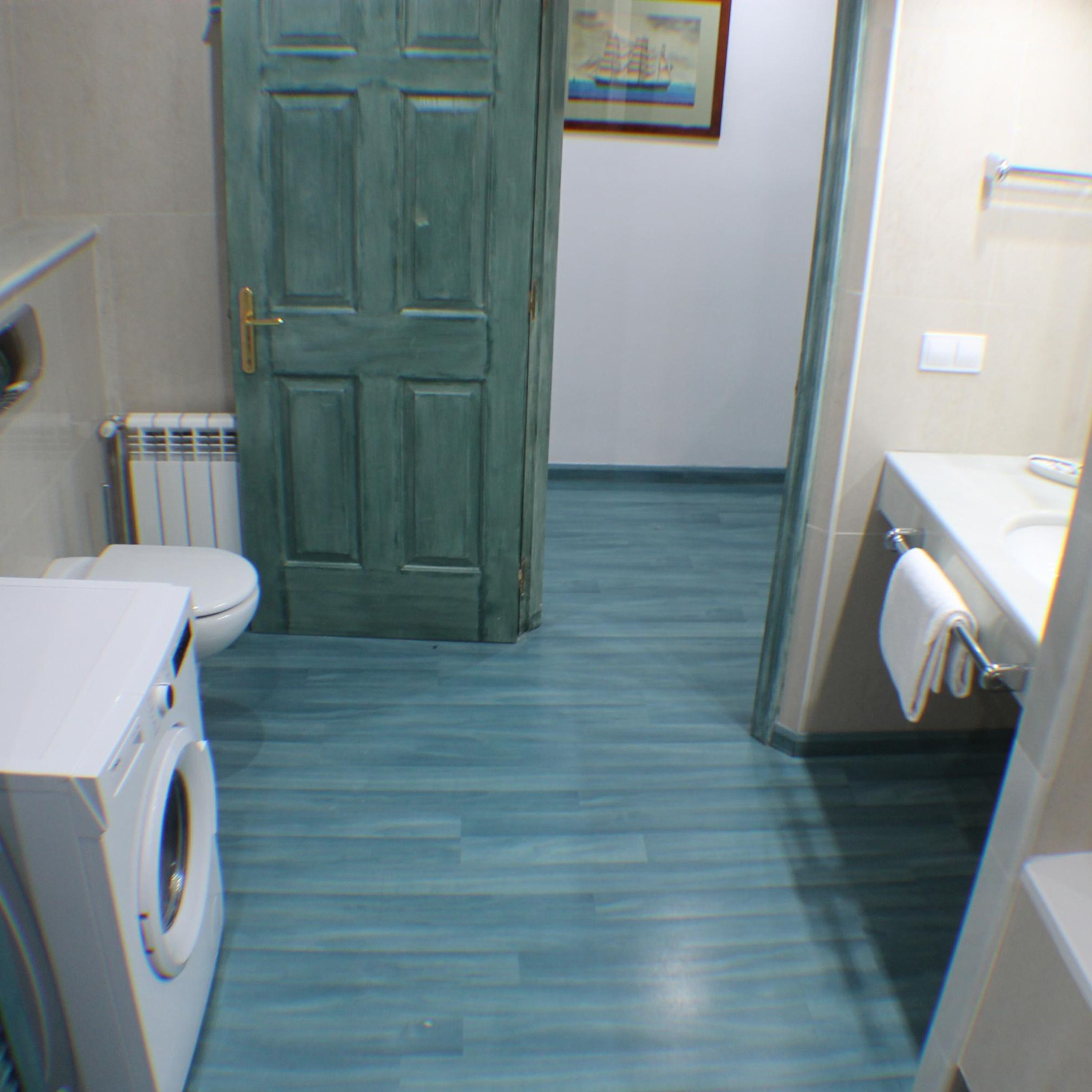 Une petite salle de bain comprenant un lave-linge, des toilettes et un lavabo.