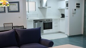 A modern living room with a sofa, a dining table, and a kitchen in the background. - Avenida 5C in Roses With 2 Bedrooms and 2 Bathrooms (Roses)
