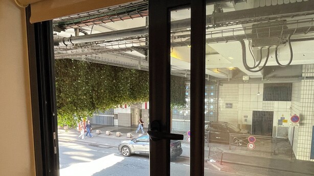 A window view of a street with a parked car and pedestrians. - Close to the Eiffel Tower, tiny triplex apartment on the banks of the Seine in Paris.  (Paris)