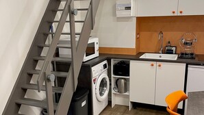 A compact kitchen with a built-in washing machine, a microwave, and a sink. - Close to the Eiffel Tower, tiny triplex apartment on the banks of the Seine in Paris.  (Paris)