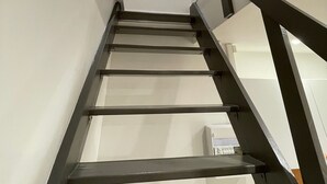 A modern staircase with a minimalist design, featuring a metal handrail and a glass panel on the wall. - Close to the Eiffel Tower, tiny triplex apartment on the banks of the Seine in Paris.  (Paris)
