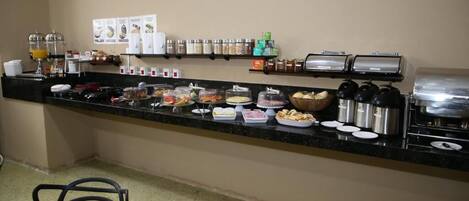 Un mostrador de buffet con diversos alimentos, salsas y una máquina de café.