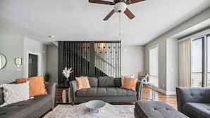 Ein modernes Wohnzimmer mit einem grauen Sofa, einem runden Couchtisch und einer Treppe mit Geländer.