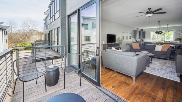 Ein modernes Apartment mit Balkon, einem Wohnzimmer inklusive Sofa und Fernseher sowie einer Küchenzeile.