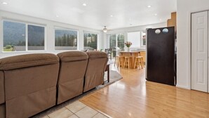 Una cocina moderna con un refrigerador negro, suelo de madera y ventanas amplias que ofrecen vistas al exterior.