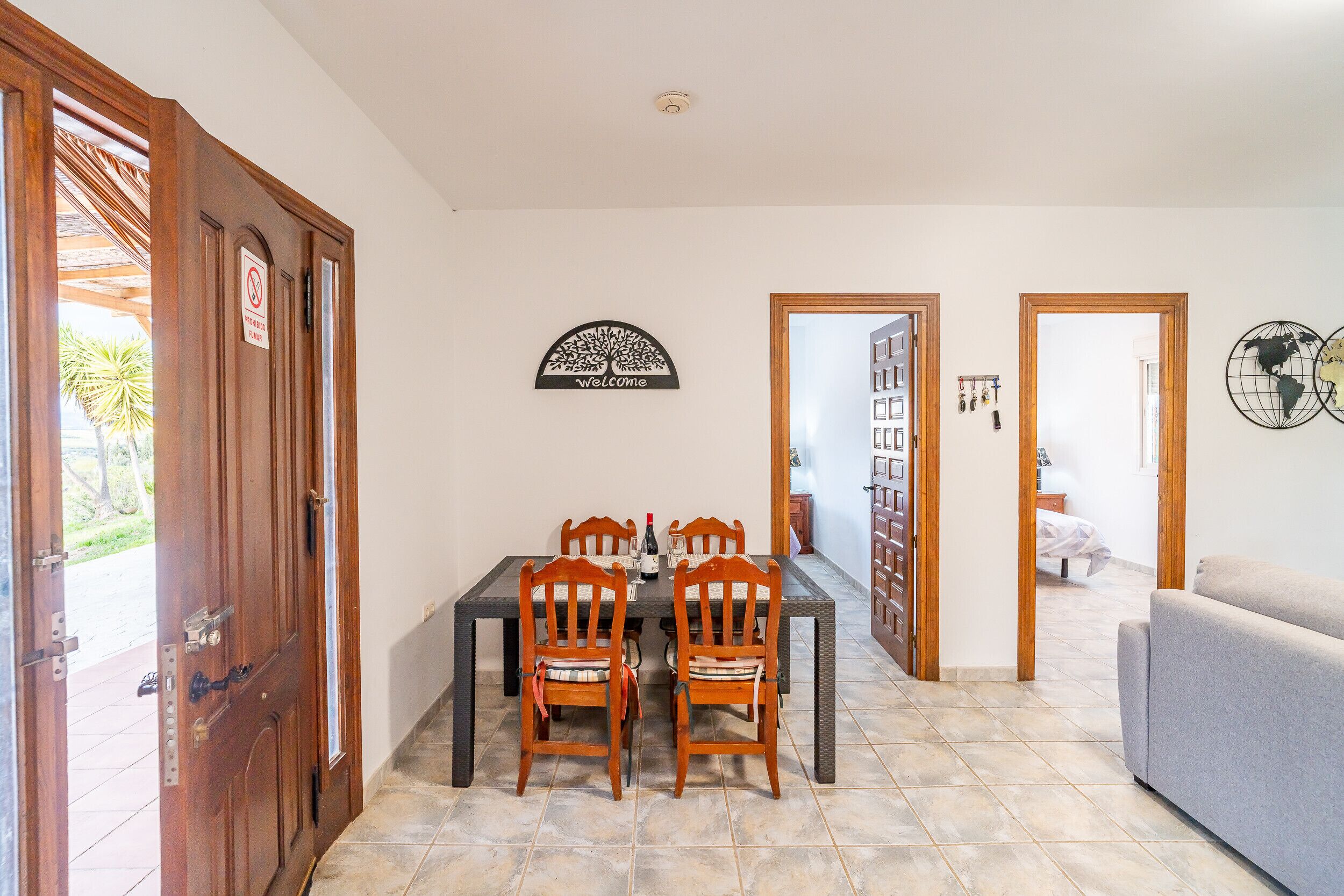 Un coin repas avec une table et des chaises, une pancarte « Bienvenue » et un globe décoratif accroché au mur.
