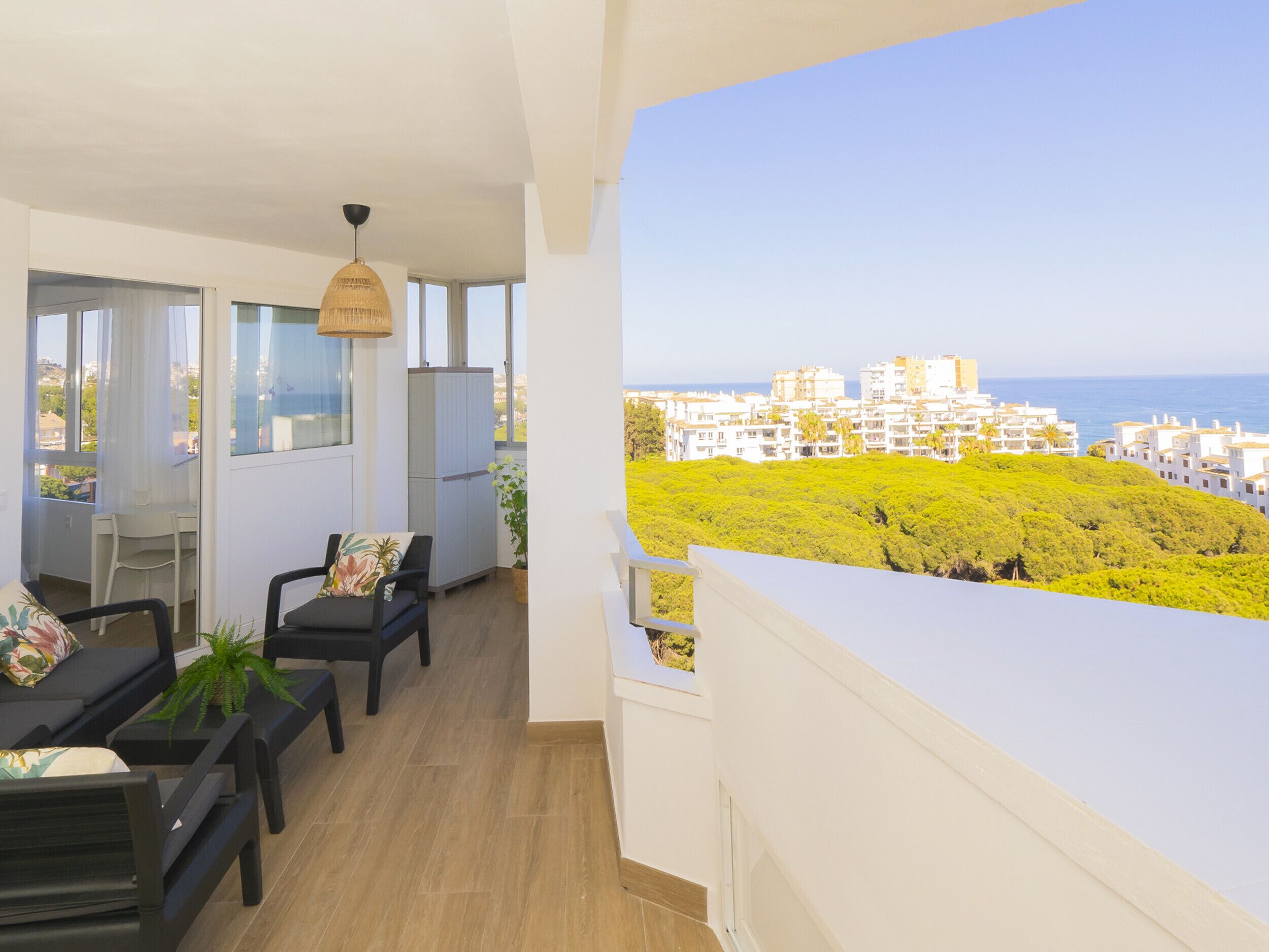 A balcony with a view of a coastal town and greenery.