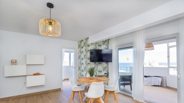 Een moderne eetruimte met een ronde tafel, witte stoelen en een hanglamp.