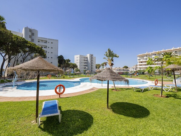 Un espace piscine comprenant plusieurs bassins, des chaises longues et des parasols.