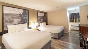 A hotel room with two beds, a desk, and a view of a landscape painting. - Home Away From Home (Prince George)