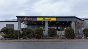 A commercial building with a 'Clay Oven Grill' and 'Super 8' signage, featuring a stone facade and a covered entrance area. - Home Away From Home (Prince George)