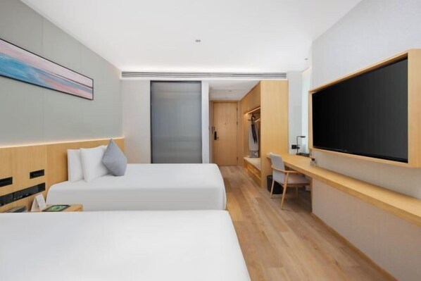 Une chambre d’hôtel moderne équipée de deux lits, d’un bureau, d’une télévision et d’une armoire à portes coulissantes.