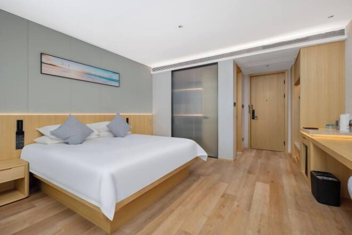 A modern hotel room with a bed, bedside table, and a painting on the wall.