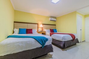 Two single beds with headboards and bedside tables, air conditioning and a ceiling light fixture.