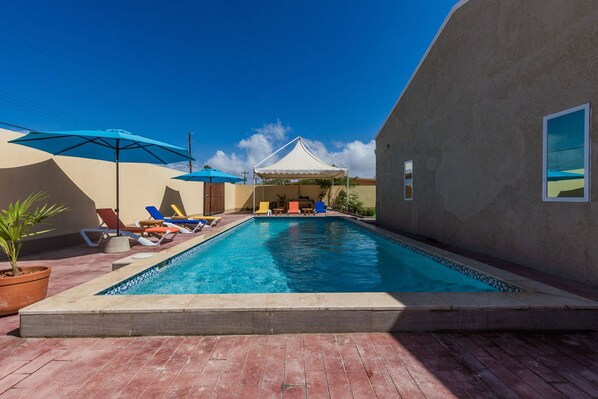 Relax by the pool surrounded by lounge chairs and umbrellas.
