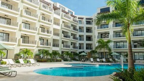 A multi-story hotel with balconies, a swimming pool, and lounge chairs. - 2BR 2BA Duplex w Amazing Views Pool Amenities (Noord)