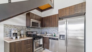 A modern kitchen with dark wood cabinets, stainless steel appliances, a built-in microwave, and a dishwasher. - 2BR 2BA Duplex w Amazing Views Pool Amenities (Noord)